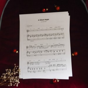 Sheet music to "A Silent Night" surrounded by Christmas themed decorations.