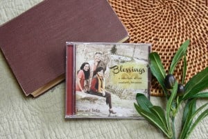 CD of "Blessings: A Collection of Our Mother's Favorites". The music is surrounded by a bible and a small leafy plant.