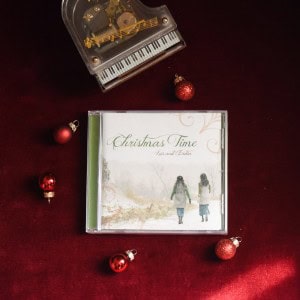 CD of "Christmas Time". The music is surrounded by a model piano and Christmas Bulbs on a red background.