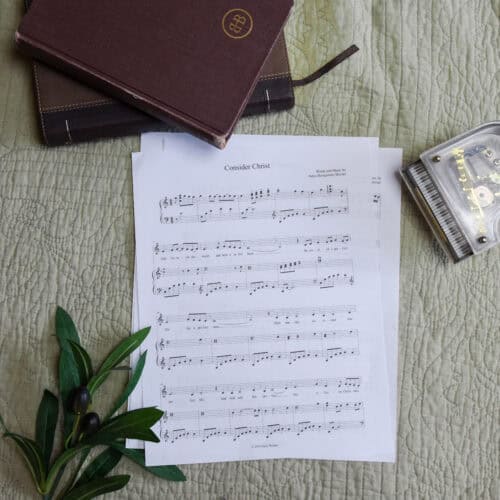 Sheet music to "Consider Christ". The music is surrounded by a model piano, a bible, and a small leafy plant.