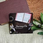 CD of "Journey On". The music is surrounded by a bible, and a small leafy plant.