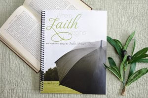 Sheet music book "Where Faith Begins" laying on an open bible with a green plant beside it.