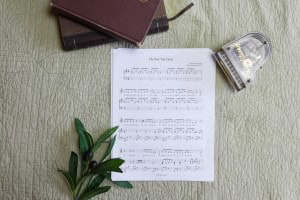 Sheet music to "The Way You Came". The music is surrounded by a model piano, a bible, and a small leafy plant.