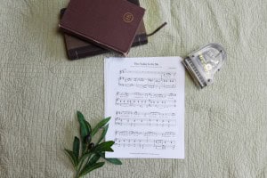 Sheet music to "This Valley Is For Me". The music is surrounded by a model piano, a bible, and a small leafy plant.