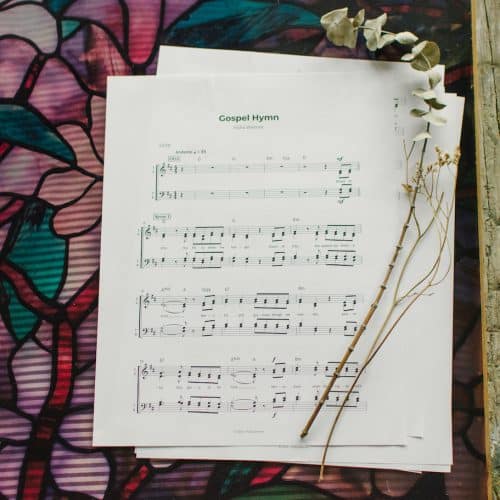 The sheet music to "Gospel Hymn" laying on a table surrounded by flowers.