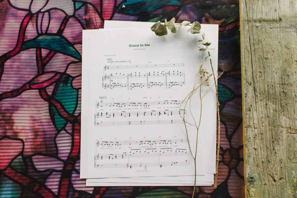 Sheet music to "Grace in me" laying on a table surrounded by floral arrangements.