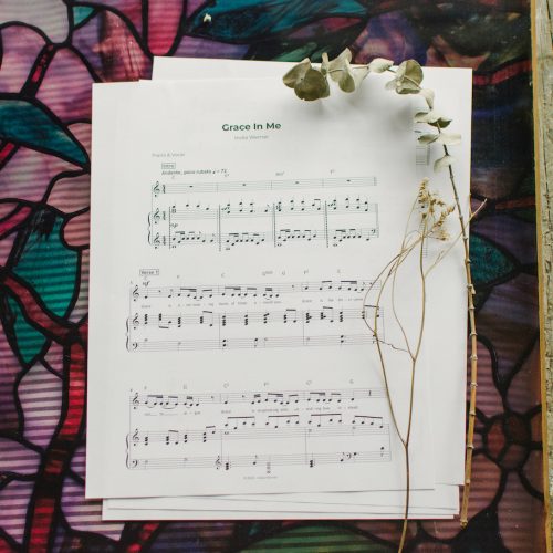 Sheet music to "Grace in me" laying on a table surrounded by floral arrangements.