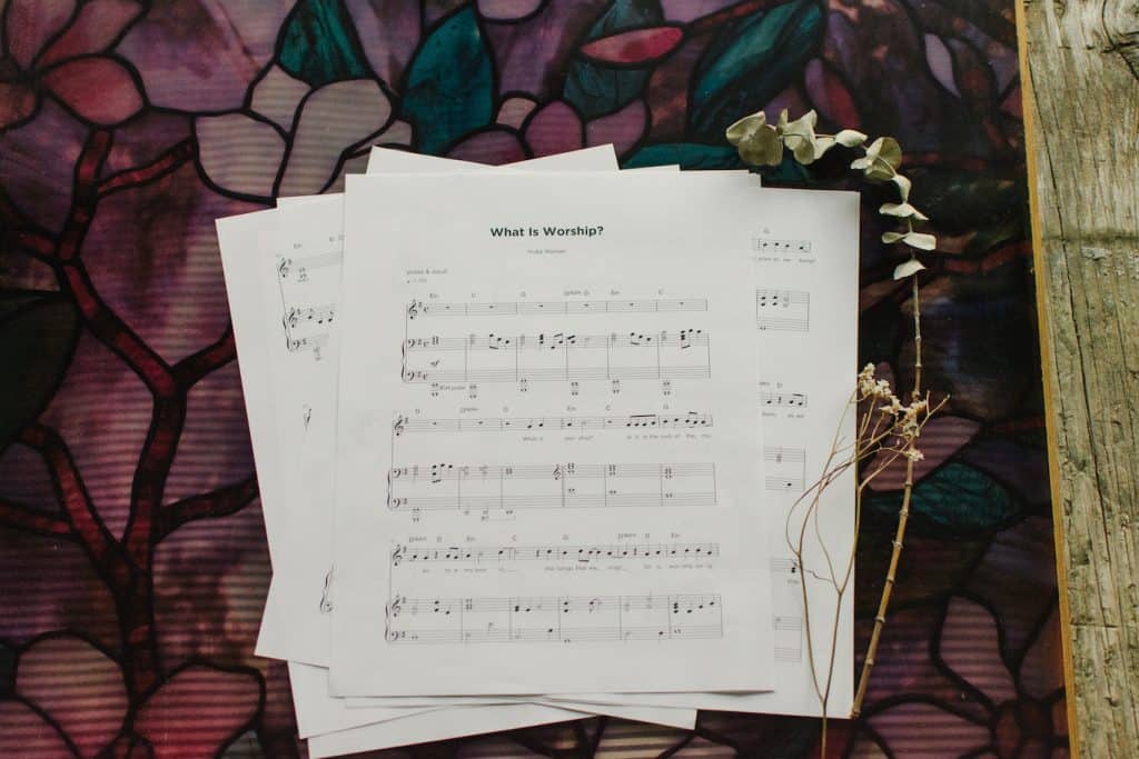 The Sheet music to "What is Worship" splayed out of a table with floral arrangements around it.
